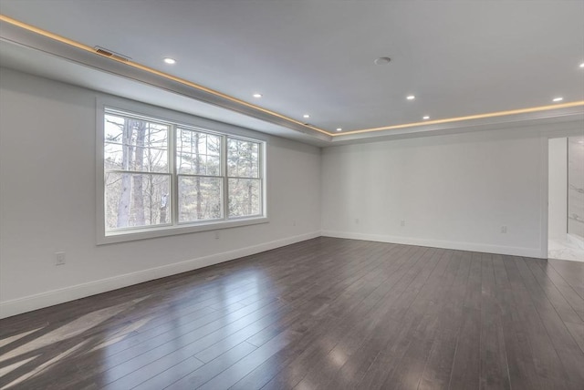 spare room with a tray ceiling and dark hardwood / wood-style floors