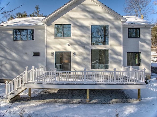 snow covered rear of property with a wooden deck