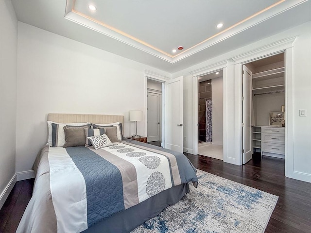 bedroom featuring a closet, a spacious closet, dark hardwood / wood-style floors, and a raised ceiling