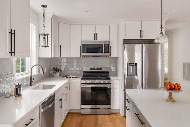 kitchen featuring pendant lighting, stainless steel appliances, white cabinets, and sink