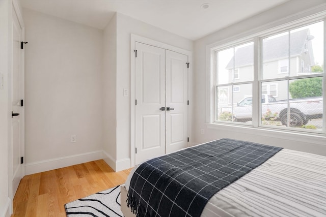 bedroom featuring multiple windows, light hardwood / wood-style flooring, and a closet