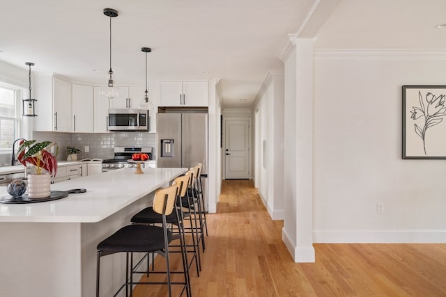 kitchen featuring light hardwood / wood-style flooring, stainless steel appliances, white cabinets, and pendant lighting