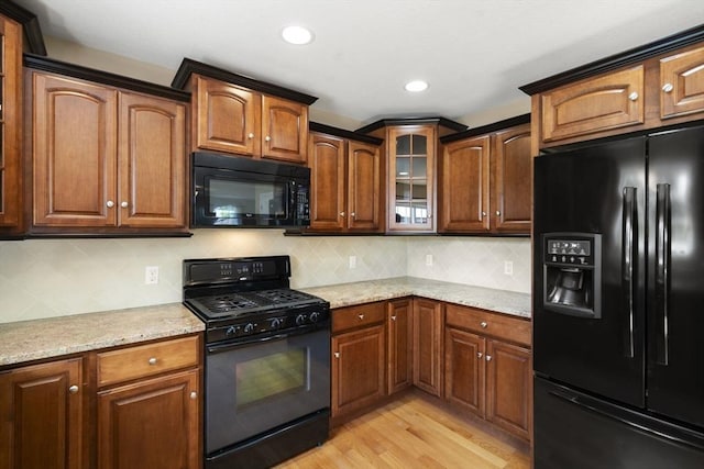 161 Bear Hole Rd, West Springfield, MA 01089 - kitchen with glass insert cabinets, light stone countertops, black appliances, and light wood-type flooring