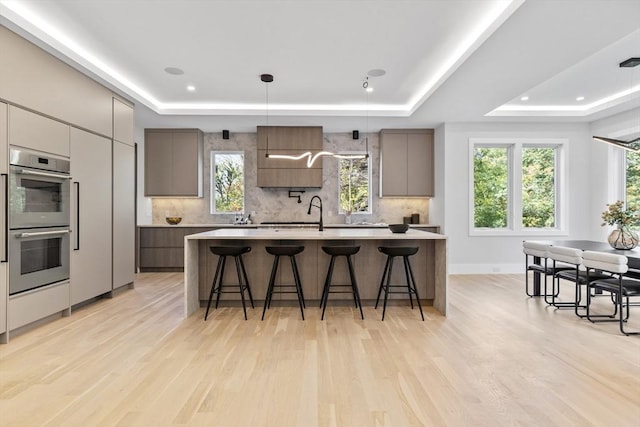 kitchen featuring a kitchen breakfast bar, a raised ceiling, and stainless steel double oven