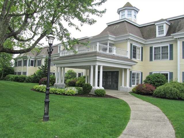 view of front facade featuring a front lawn and a balcony