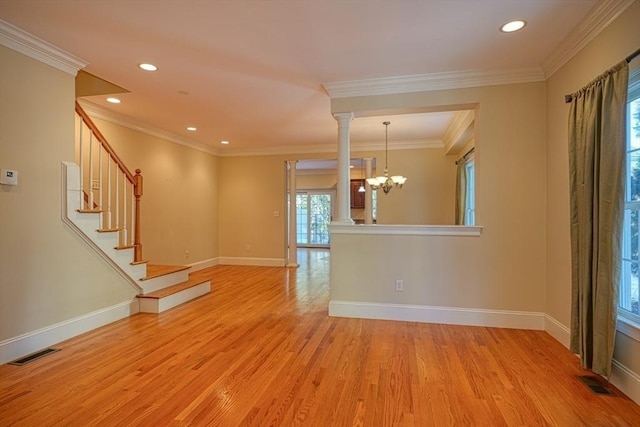 interior space with a notable chandelier, ornamental molding, light wood-type flooring, and ornate columns