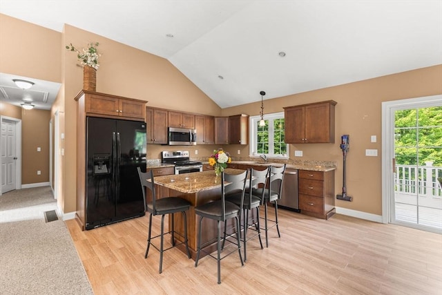 33 Beaver St, Whitman, MA 02382 - kitchen with appliances with stainless steel finishes, light wood-style flooring, a kitchen bar, high vaulted ceiling, and a center island