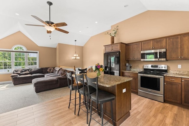 33 Beaver St, Whitman, MA 02382 - kitchen featuring stainless steel appliances, vaulted ceiling, light wood-type flooring, a breakfast bar, and ceiling fan