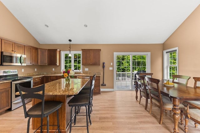 33 Beaver St, Whitman, MA 02382 - kitchen with appliances with stainless steel finishes, lofted ceiling, light wood finished floors, light stone countertops, and a kitchen island