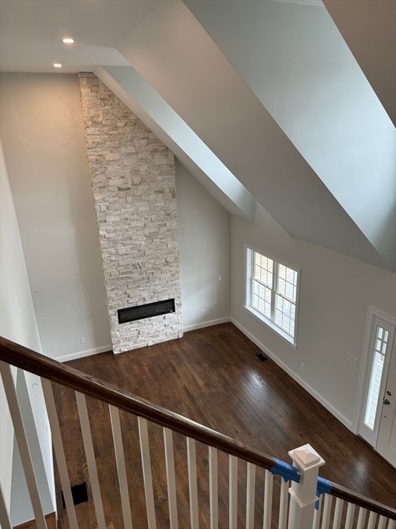 unfurnished living room featuring a fireplace, wood-type flooring, and vaulted ceiling with skylight