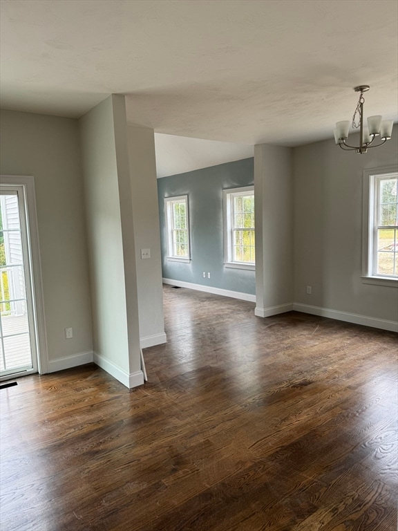 unfurnished room with an inviting chandelier and dark wood-type flooring