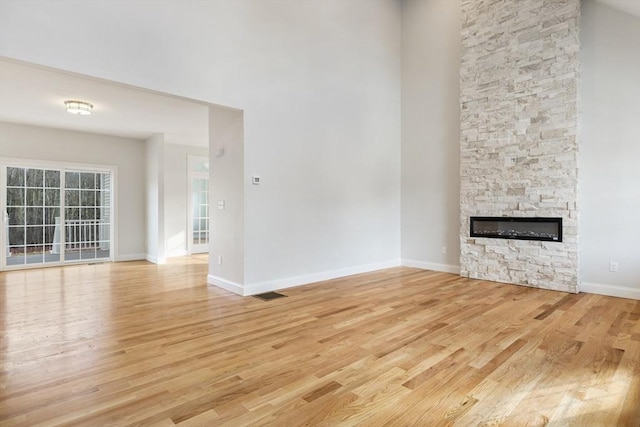 unfurnished living room featuring light hardwood / wood-style floors and a stone fireplace