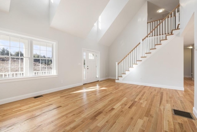 foyer with light wood-type flooring and a towering ceiling