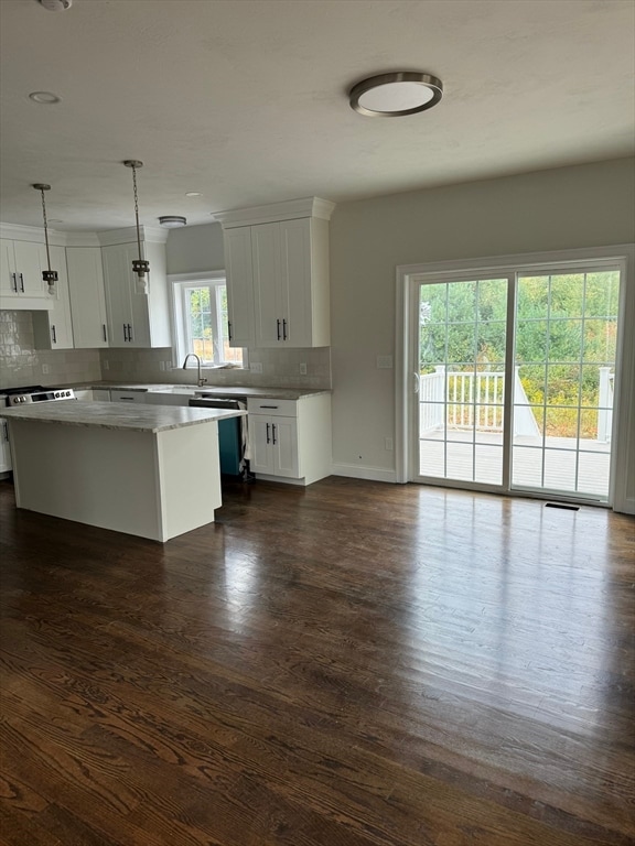 kitchen with backsplash, a center island, white cabinets, and decorative light fixtures