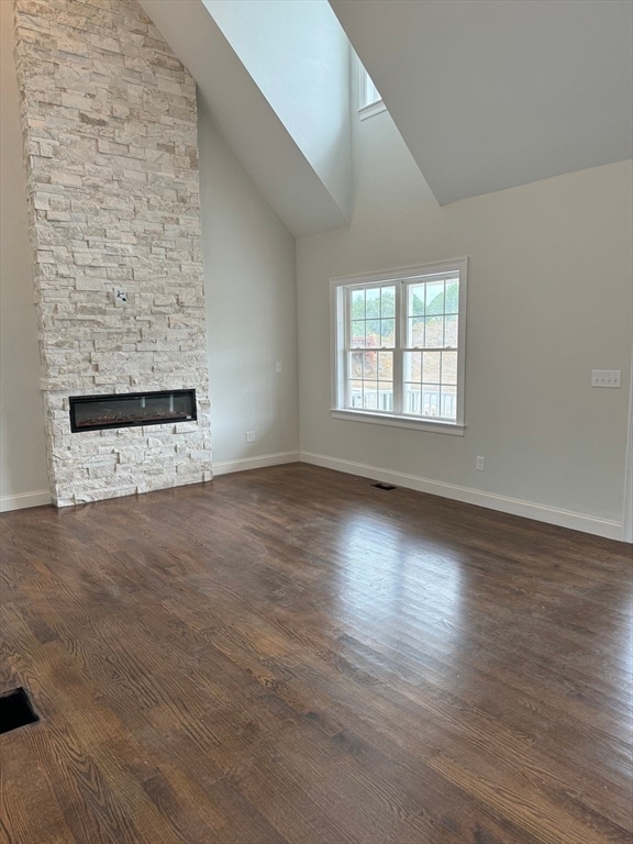 unfurnished living room featuring a fireplace, dark hardwood / wood-style flooring, and high vaulted ceiling