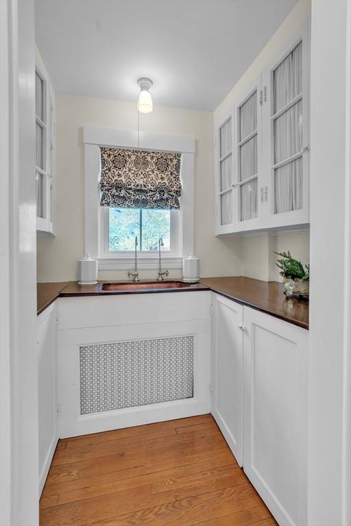 40 Pleasant St, Dover, MA 02030 - kitchen featuring a sink, white cabinetry, light wood finished floors, and dark countertops