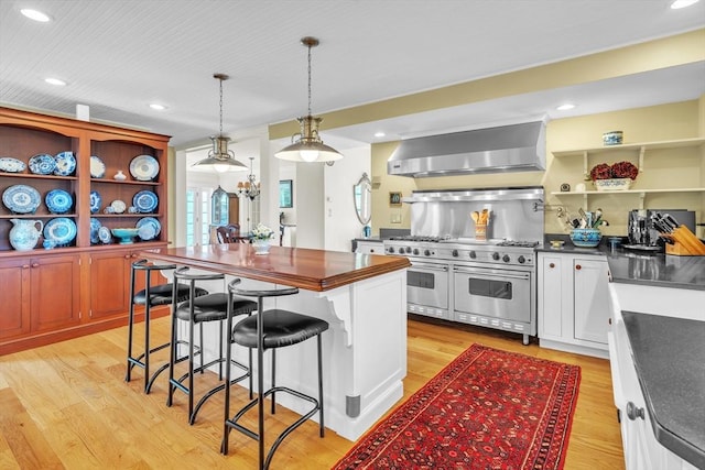 40 Pleasant St, Dover, MA 02030 - kitchen featuring wall chimney range hood, open shelves, a breakfast bar area, range with two ovens, and recessed lighting