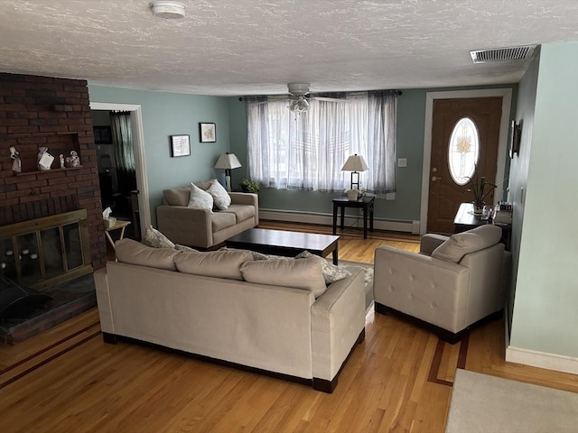 living room featuring light wood finished floors, a fireplace, visible vents, and a wealth of natural light