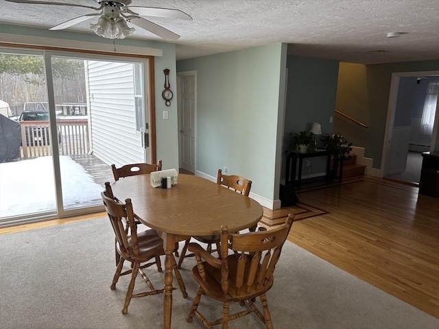 dining room with a ceiling fan, a baseboard heating unit, a textured ceiling, wood finished floors, and baseboards