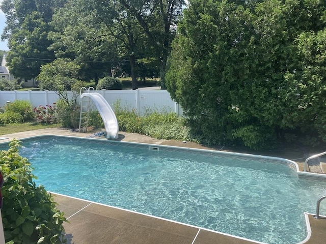 view of swimming pool featuring a water slide, a fenced backyard, and a fenced in pool