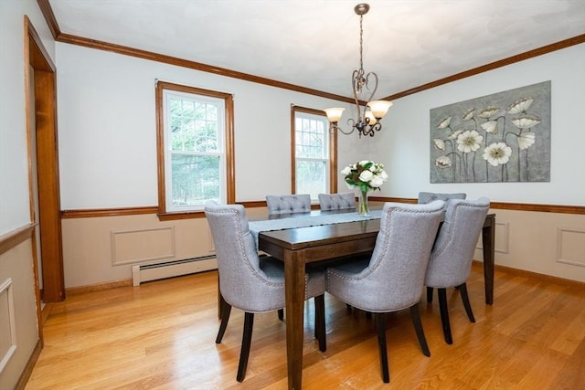 dining room with light wood-style floors, crown molding, a baseboard heating unit, and a chandelier