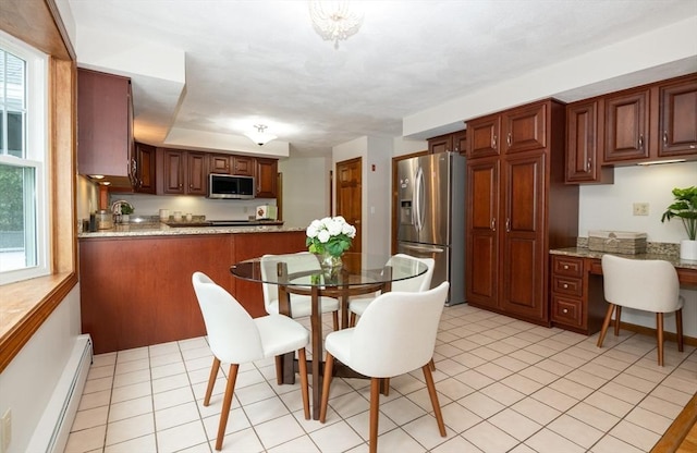 dining space featuring a wealth of natural light, light tile patterned floors, built in study area, and a baseboard radiator