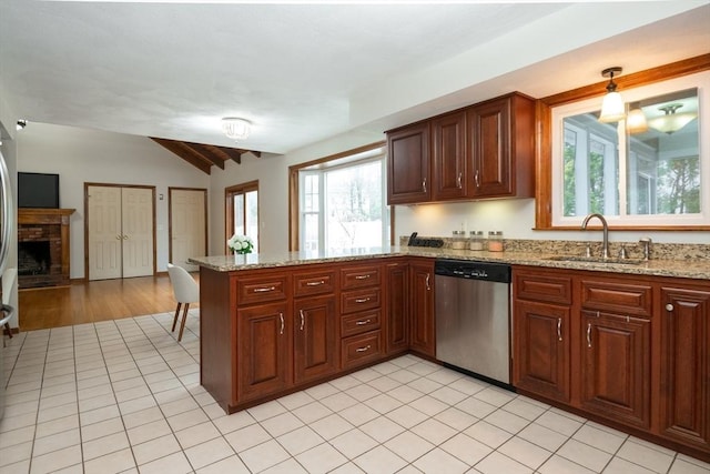 kitchen with stainless steel dishwasher, a brick fireplace, a peninsula, lofted ceiling, and a sink