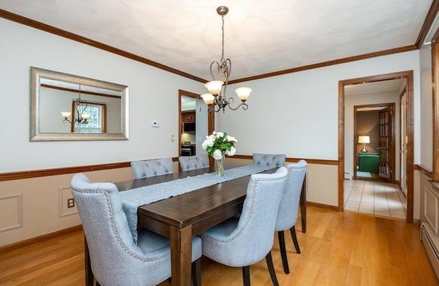 dining space with ornamental molding, light wood-style floors, baseboard heating, a chandelier, and a baseboard radiator