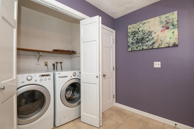 laundry room with baseboards, laundry area, light tile patterned flooring, and washer and clothes dryer