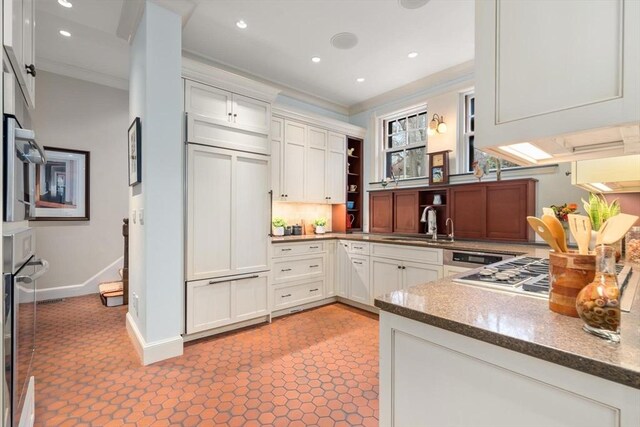 kitchen featuring ornamental molding, paneled fridge, stainless steel oven, open shelves, and a sink