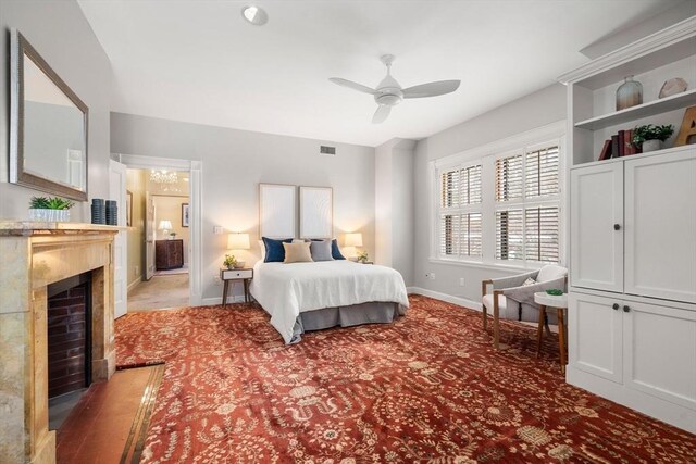 bedroom featuring a fireplace with flush hearth, visible vents, baseboards, and a ceiling fan