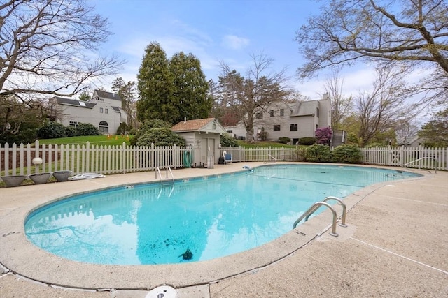 view of swimming pool featuring a patio area, fence, a fenced in pool, and an outbuilding