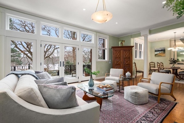 interior space with baseboards, ornamental molding, wood finished floors, french doors, and ornate columns