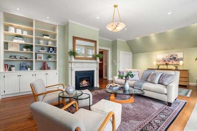 living room with recessed lighting, wood finished floors, baseboards, a lit fireplace, and ornamental molding