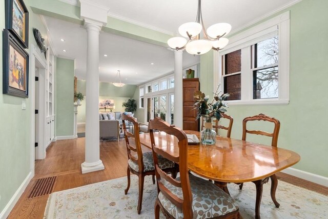 dining area with light wood finished floors, decorative columns, visible vents, and crown molding