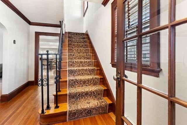 stairs with hardwood / wood-style floors and crown molding