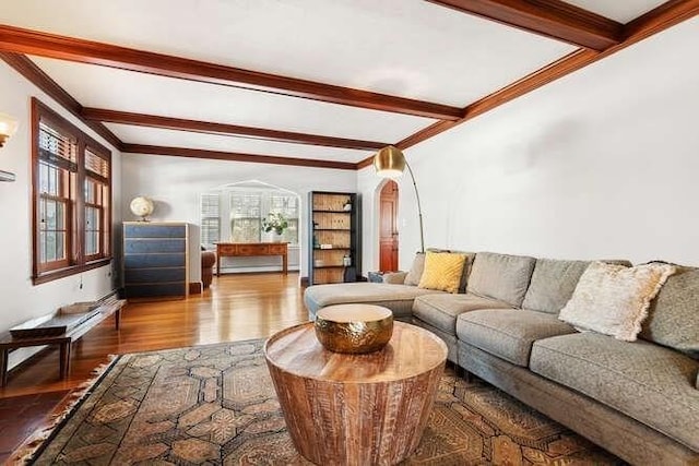 living room with wood-type flooring, ornamental molding, and beam ceiling