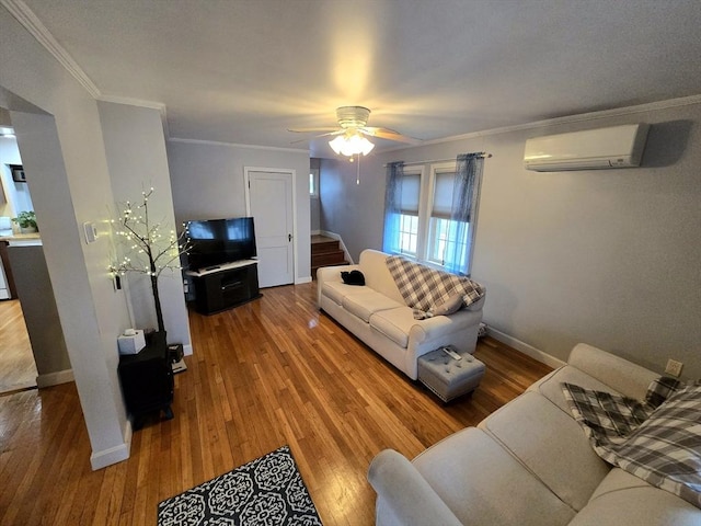 living room with a wall mounted air conditioner, hardwood / wood-style flooring, ceiling fan, and crown molding