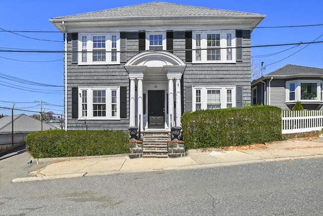 view of front of property featuring roof with shingles and fence