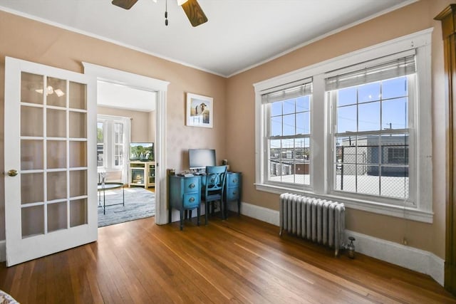 interior space with a ceiling fan, baseboards, radiator, ornamental molding, and hardwood / wood-style flooring