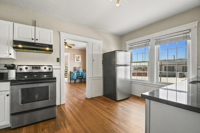 kitchen featuring under cabinet range hood, appliances with stainless steel finishes, wood finished floors, and white cabinets
