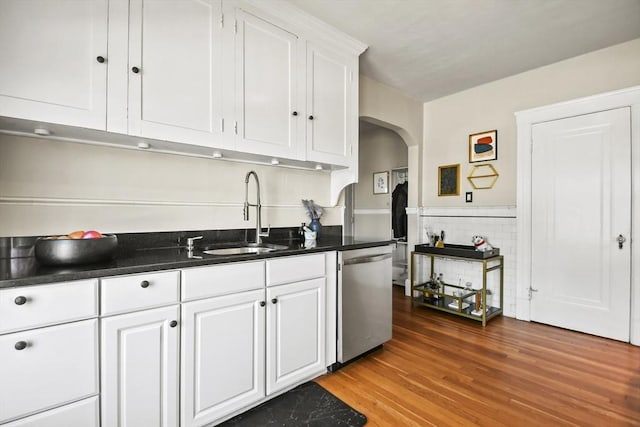 kitchen featuring a sink, dark countertops, white cabinets, arched walkways, and dishwasher