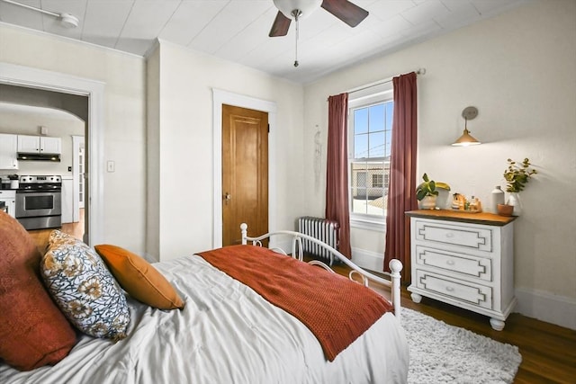 bedroom with radiator, wood finished floors, baseboards, and ceiling fan