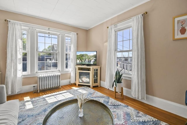sitting room with baseboards, radiator, ornamental molding, and wood finished floors