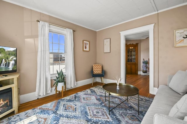 interior space featuring crown molding, wood finished floors, baseboards, and a glass covered fireplace