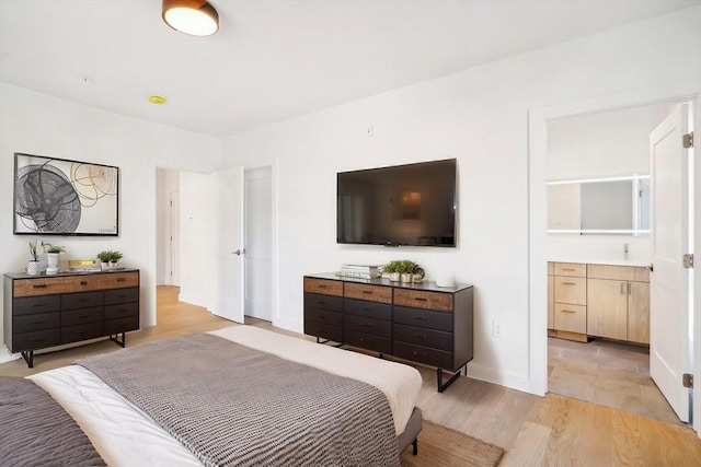 bedroom with light hardwood / wood-style flooring and ensuite bath