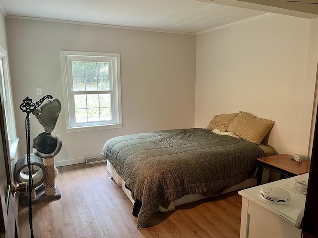 bedroom featuring light wood-style flooring, ornamental molding, and baseboards