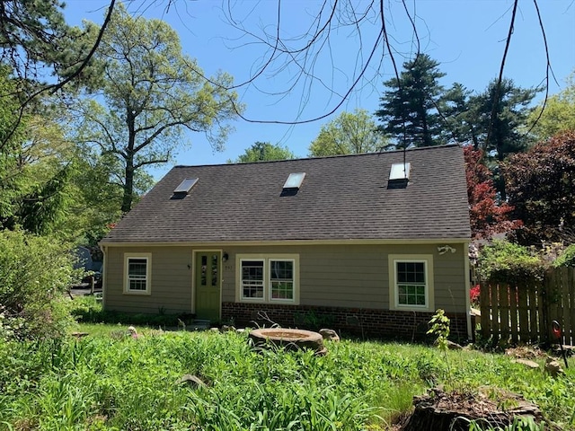 rear view of property featuring fence and a shingled roof