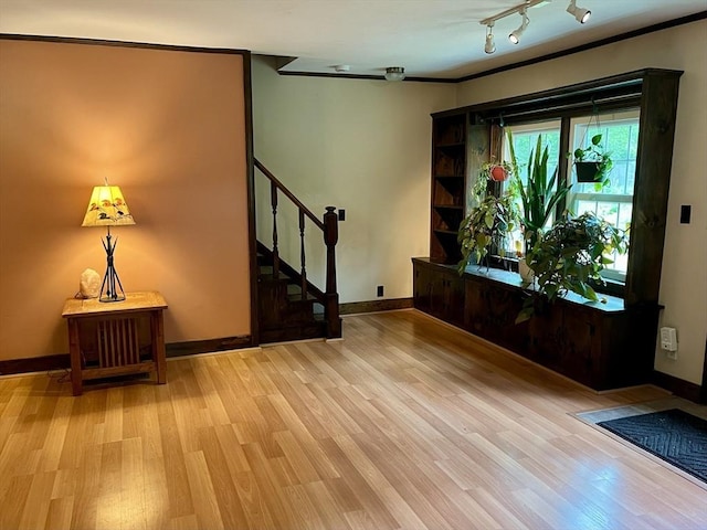 foyer featuring light wood-type flooring, stairs, baseboards, and crown molding