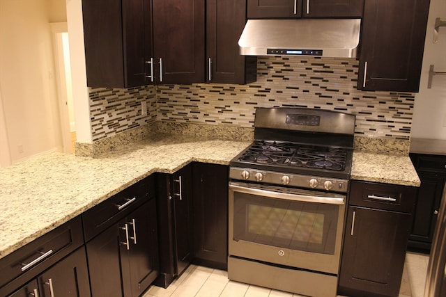 kitchen with stainless steel gas range oven, light stone countertops, dark brown cabinetry, and range hood